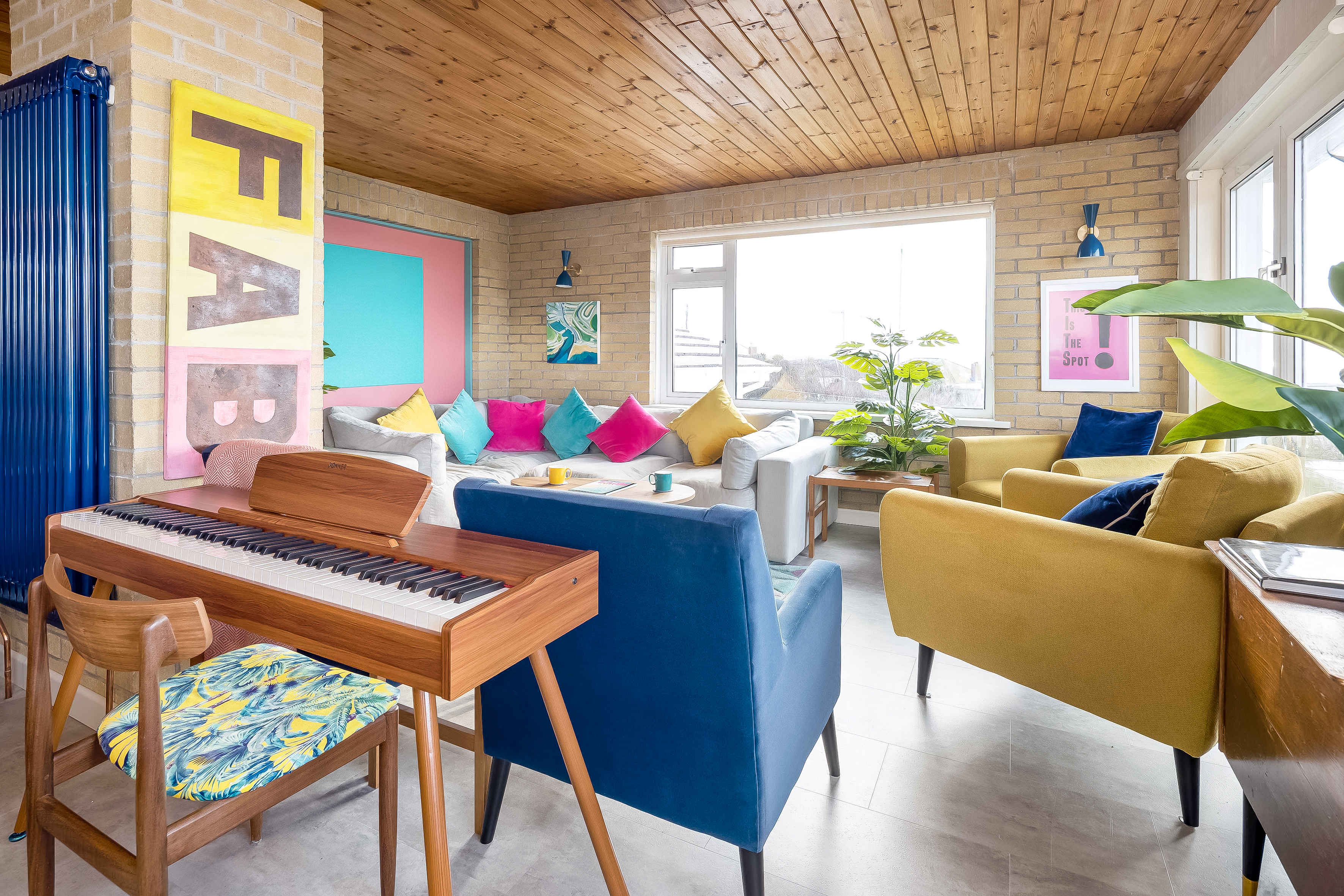 Comfortable living space with colourful cushions and coastal artwork