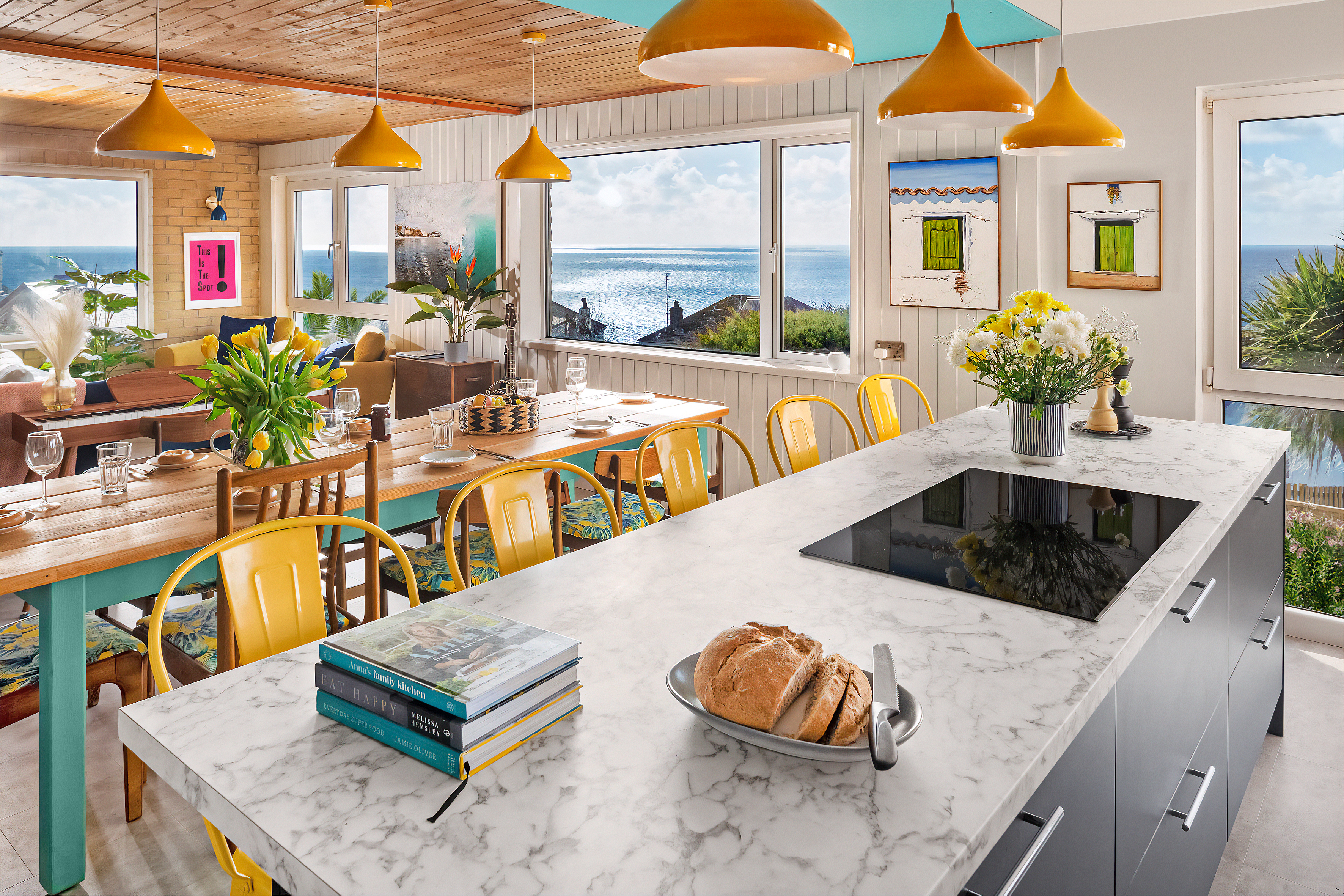 Kitchen and dining area panorama with sea views and yellow chairs